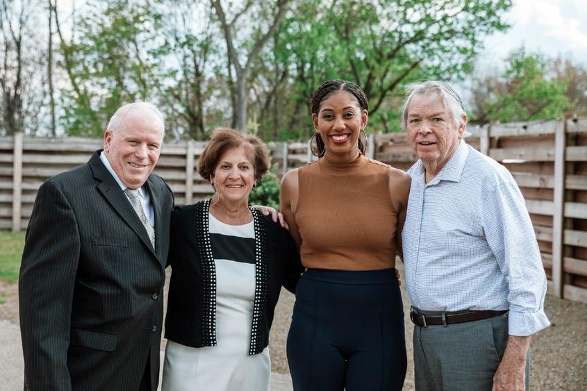 Four individuals stand smiling and posing for photo